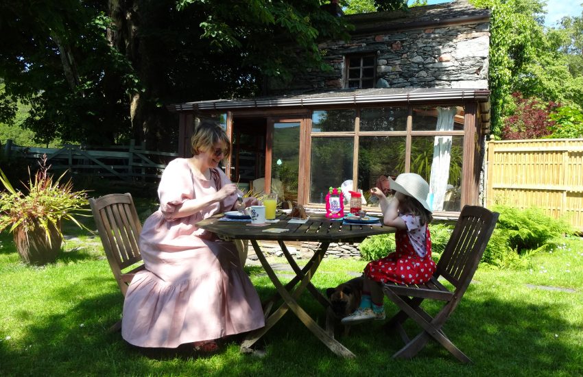 Mother and daughter enjoying breakfast in a sunny cottage garden